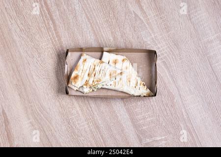 Two pieces of folded pita bread with filling in a cardboard takeaway box. Stock Photo