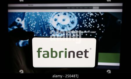 Germany. 27th June, 2024. In this photo illustration, a person is holding a cellphone with the logo of Thai manufacturing company Fabrinet Co. Ltd. in front of business webpage. (Photo by Timon Schneider/SOPA Images/Sipa USA) *** Strictly for editorial news purposes only *** Credit: Sipa USA/Alamy Live News Stock Photo