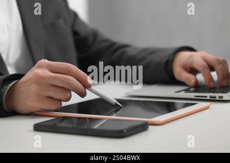 Businessman using different devices at white table indoors, closeup. Modern technology Stock Photo