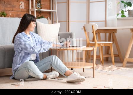 Beautiful woman using laptop on coffee table at home Stock Photo
