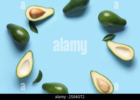 Frame made of fresh ripe avocados and leaves on blue background Stock Photo