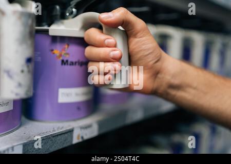 Close-up cropped shot of unrecognizable auto painter male choosing appropriate color for car dyeing, make choice from cans. Mechanic selection colors Stock Photo