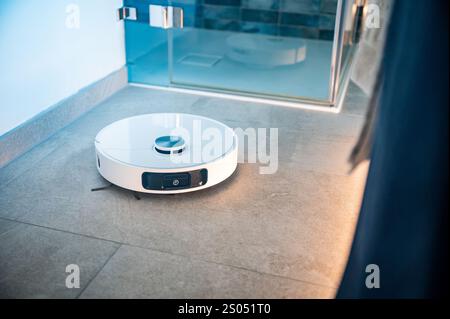 Robot vacuum cleaner with camera and sensors cleans a bathroom floor Stock Photo