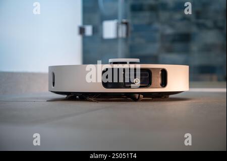 Robot vacuum cleaner with camera and sensors cleans a tiled floor Stock Photo