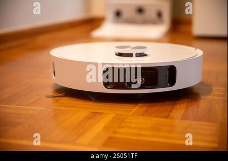 Robot vacuum cleaner with camera and sensors cleans a wooden floor Stock Photo