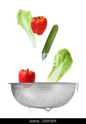 Different fresh vegetables falling into colander on white background Stock Photo