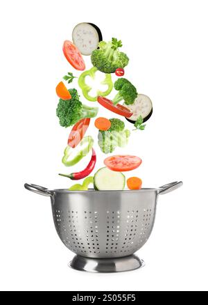 Different fresh vegetables falling into colander on white background Stock Photo