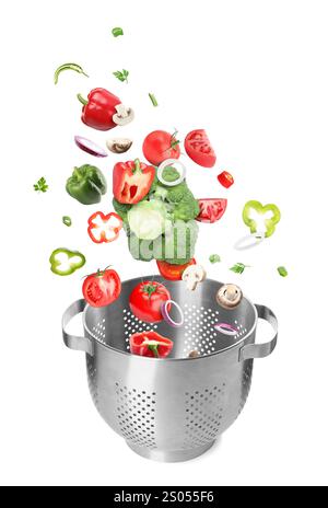 Different fresh vegetables falling into colander on white background Stock Photo