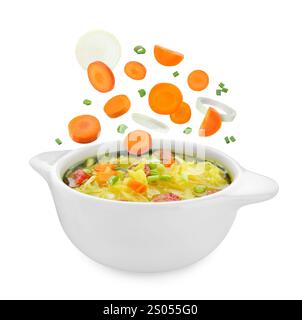 Vegetables falling into pot with soup on white background Stock Photo