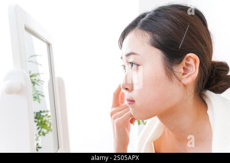 Young woman taking care of her skin in her room Stock Photo