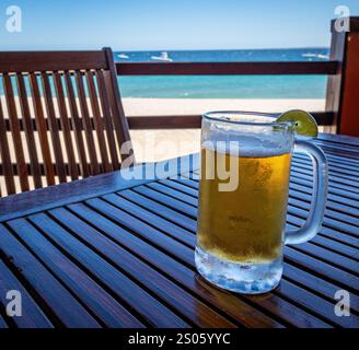 A cool mug of beer and a lime slice on a wooden table at a beachfront restaurant in Baja, California Sur, Mexico. Stock Photo