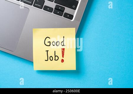 Good Job written on sticky note paper attached to laptop on blue table Stock Photo