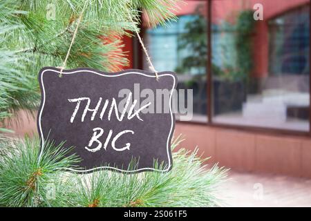 Think big symbol. Concept words Think Big on black chalk blackboard. Beautiful background with shop and tree. Business and Think big concept. Copy spa Stock Photo