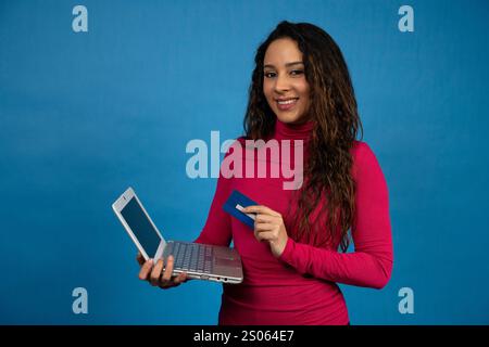 Smiling young woman holding a laptop and a credit card, ready for online shopping Stock Photo