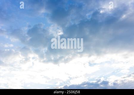 A vast sky filled with soft gray and white clouds is illuminated by gentle sunlight in the late afternoon. The clouds create a serene atmosphere, perf Stock Photo