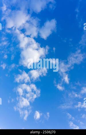 Fluffy white clouds float across a vibrant blue sky, indicating clear weather and sunshine, creating a serene and peaceful atmosphere perfect for outd Stock Photo