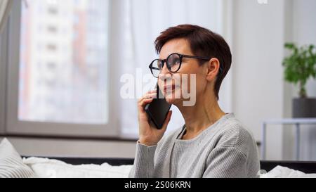 Woman speaking on the phone in a bright room Stock Photo
