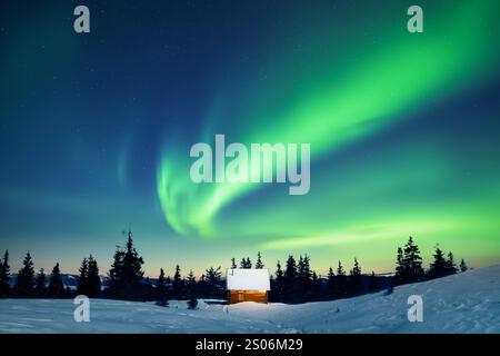 Incredible Northern lights over tiny wooden house in snowy mountains. Christmas holiday and winter vacations concept. Aurora Borealis. Polar lights Stock Photo