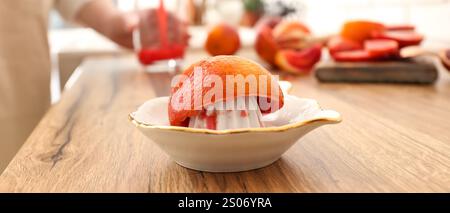 Ceramic juicer with blood orange on wooden table Stock Photo