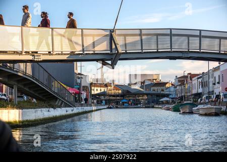 Tourists strolling near the iconic canals of Aveiro, Portugal with vibrant architecture in the background Stock Photo