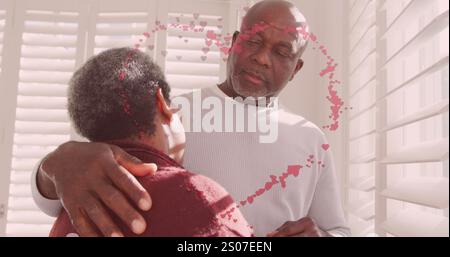 Image of hearts over senior african american couple embracing at christmas Stock Photo