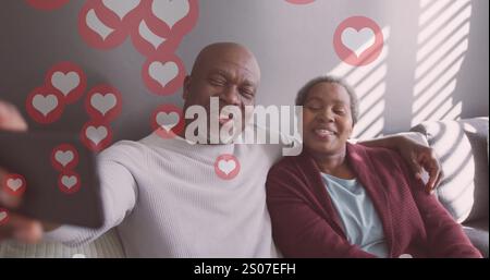 Image of hearts over senior african american couple taking selfie at christmas Stock Photo
