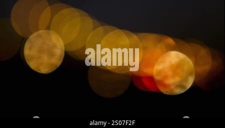Digital image of glowing golden spots of light moving against black background Stock Photo