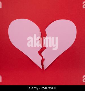 Broken heart close-up. Pink paper teared heart on red background Stock Photo