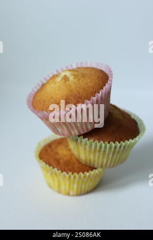 Stack of three delicious homemade golden cupcakes balancing on white background Stock Photo