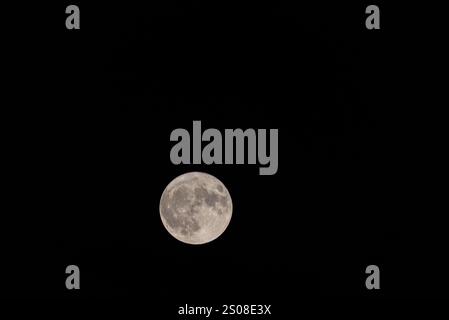 Full Moon Brilliance: Telephoto Lens Revelation.ompletely full moon through a telephoto lens. Set against the dark expanse of the night, the moon's br Stock Photo