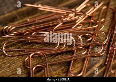 copper paper clips for the systematization of documents and paper, large-size copper paper clips on the board Stock Photo