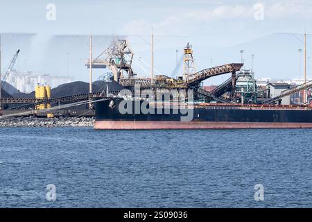 Coal is loaded onto a cargo ship with conveyer belts at a coal port with spray bars to reduce coal dust near Vancouver British Columbia Canada. Stock Photo