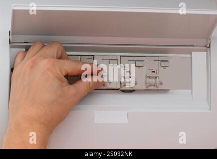 Close-up of an electrician operating a circuit breaker in a fuse box, ensuring electrical safety and power distribution. Stock Photo