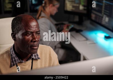 Serious experienced IT engineer looking at desktop computer screen while decoding online data or developing new software Stock Photo