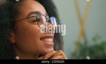 Close up African American business woman in eyeglasses looking away thinking smiling thoughtful ethnic girl happy cheerful businesswoman in glasses Stock Photo