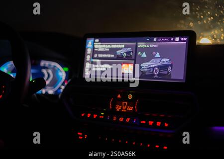 Close-up view of illuminated dashboard and digital display of BMW electric car at night, showing driving analysis and energy consumption data. Stock Photo