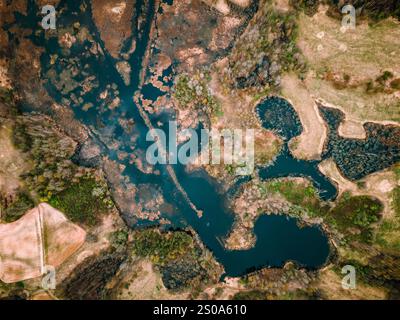 Aerial image shows a winding river amidst wetlands and fields, with dense vegetation and open grassy areas creating a natural mosaic. Stock Photo