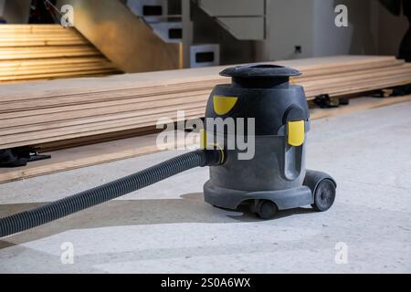 A vacuum cleaner sits on a concrete floor amidst a stack of wooden floorboards, indicating ongoing renovation work in a multi level building. Stock Photo