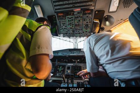 Inside pilot's cabin of ATR 72-600 (registration UR-RWA). Horizontal image of two pilots sitting in tight cockpit of regional passenger airliner. Stock Photo