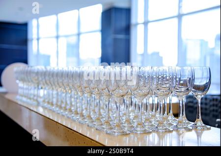 Many empty wine glasses line up waiting to pour some liquor for many invitation guests in the dinner reception celebration party in a lounge in the ho Stock Photo