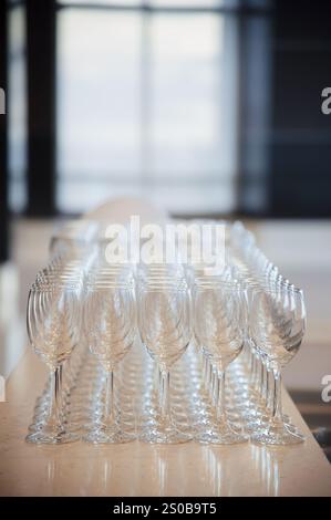 Many empty wine glasses line up waiting to pour some liquor for many invitation guests in the dinner reception celebration party in a lounge in the ho Stock Photo