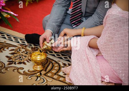 hands of the Bridge and groom holding  together to pouring holy water to paying in Thai style traditional wedding ceremony. Stock Photo