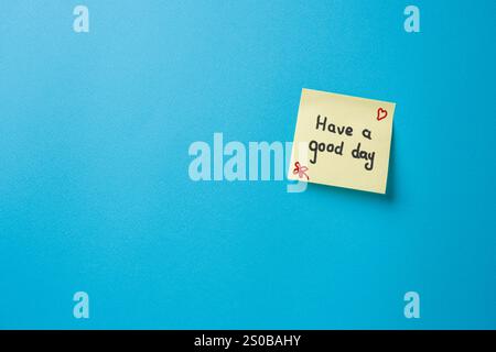 Have a good day written on yellow sticky note paper on blue background Stock Photo