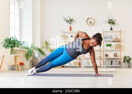 Smiling African American Woman Doing Abs Exercise In Plank Position At Home Stock Photo