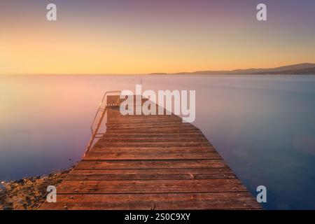 Wooden pier on Lake Trasimeno at sunset. Long exposure photography. Torricella, Magione, province of Perugia, Umbria region, Italy Stock Photo