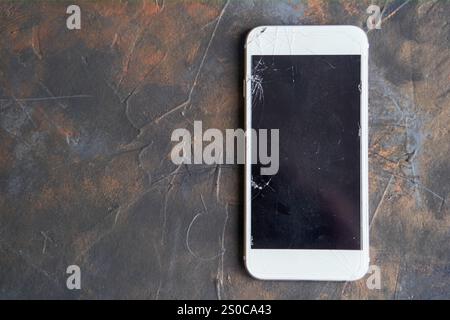 White phone with a broken screen on dark background Stock Photo