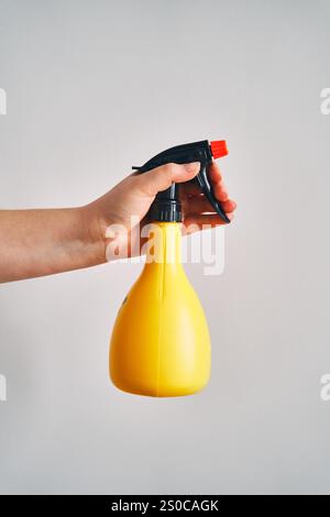 A young woman holds a spray bottle in her hand. Stock Photo