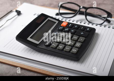Top view office accessories calculator pen clipboard notebook isolated dark grey background. Bookkeeping workplace concept. Stock Photo