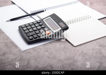 Bookkeeping workplace concept. Calculator, pen, notebook isolated on dark grey background with empty space Stock Photo
