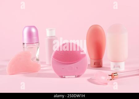 Facial cleansing brush and other body care products on pink background Stock Photo